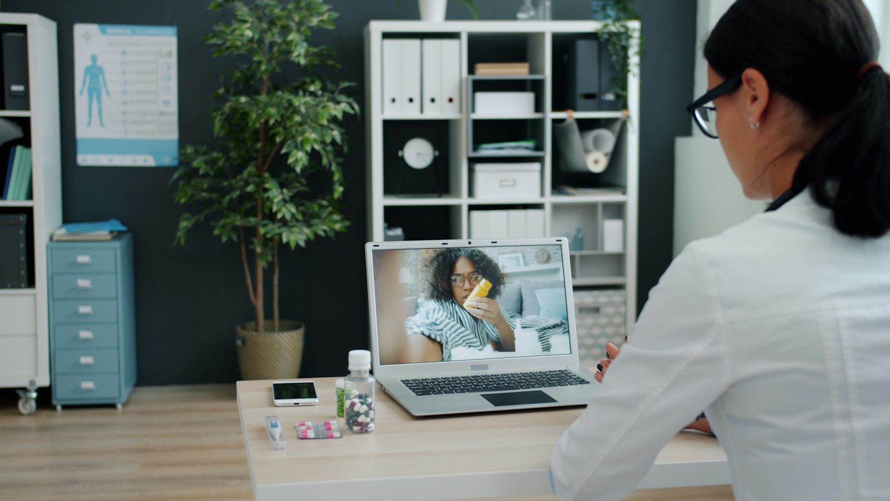 A clinician at a workstation reviewing a patient panel on screen.