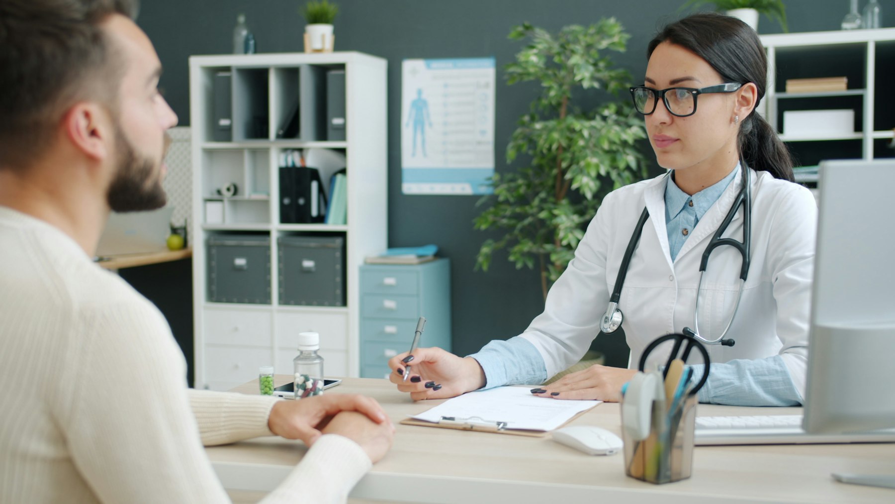 A clinician reviewing records with a patient across a desk.