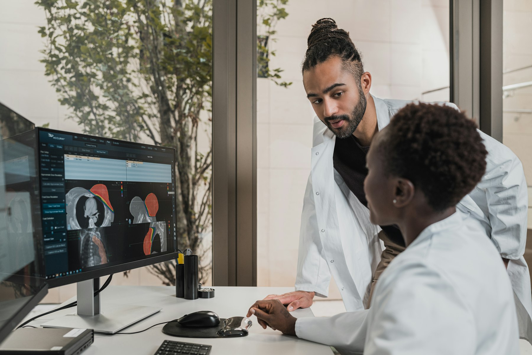 Two clinicians reviewing patient data together on a monitor.